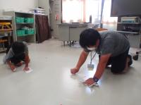 床の汚れを取る先生と子ども